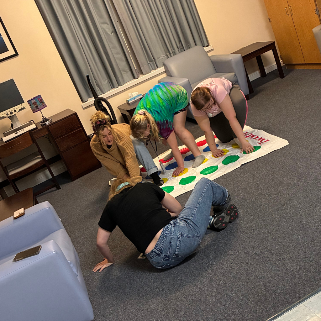 Students and staff play twister on the floor in the dorms. 