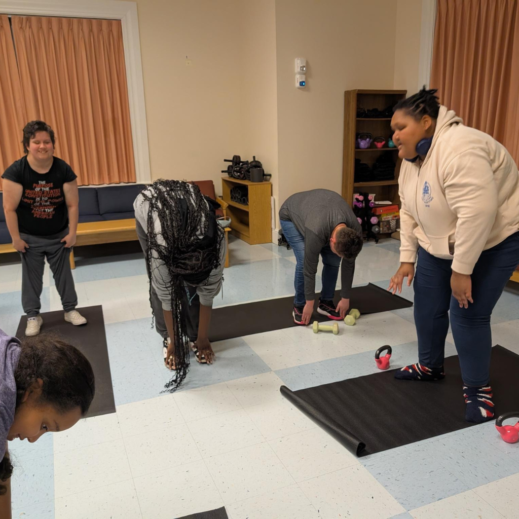 Group of girl students practice yoga together inside the dorm. 