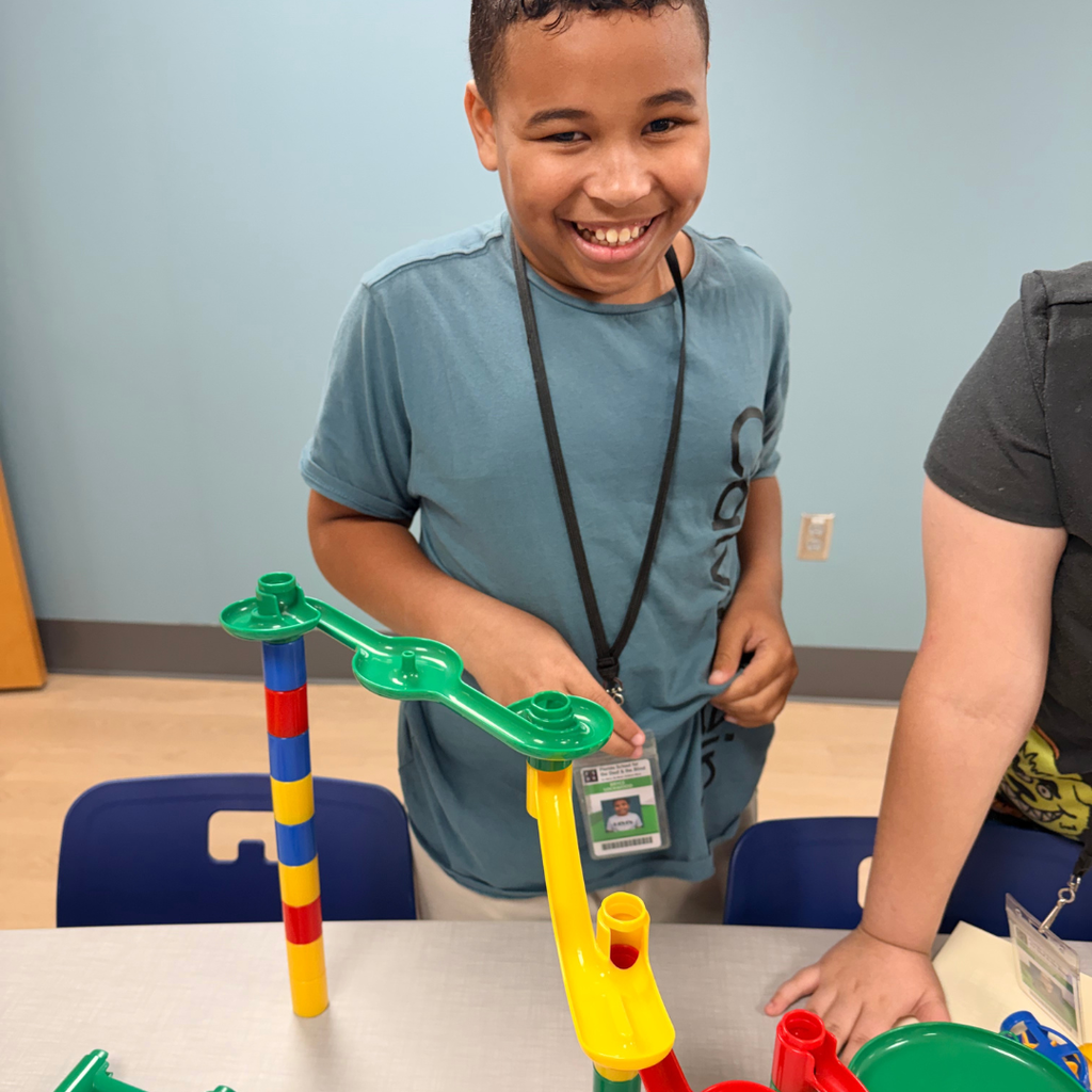 A student smiles and plays with the toys on the table. 