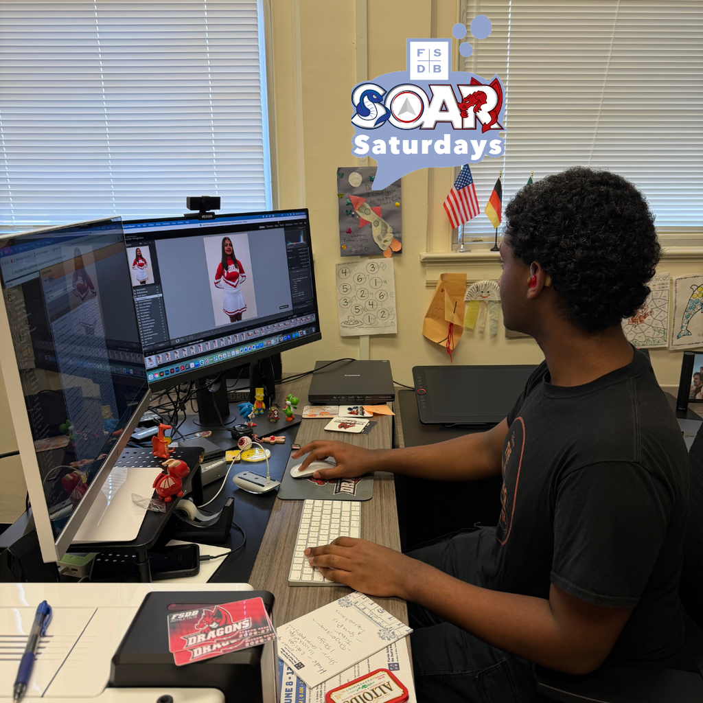 Senai is sitting at a desk editing the cheerleading photos.