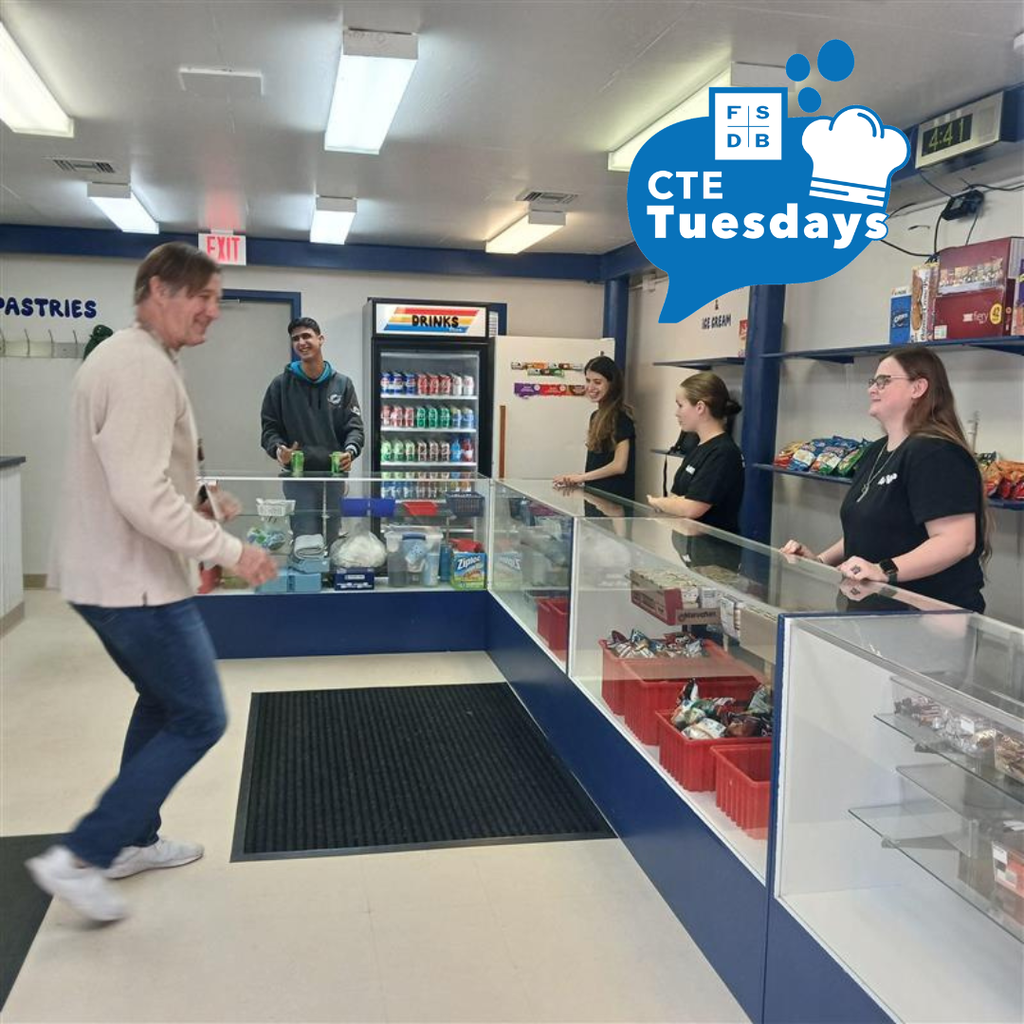 Wide shot photo of Raymond Warehouse workers standing around while a customer walks up to purchase something.