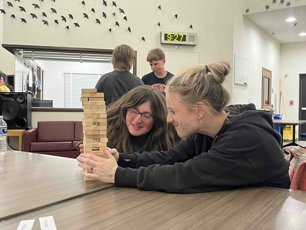 A student and staff member play jenga together. 