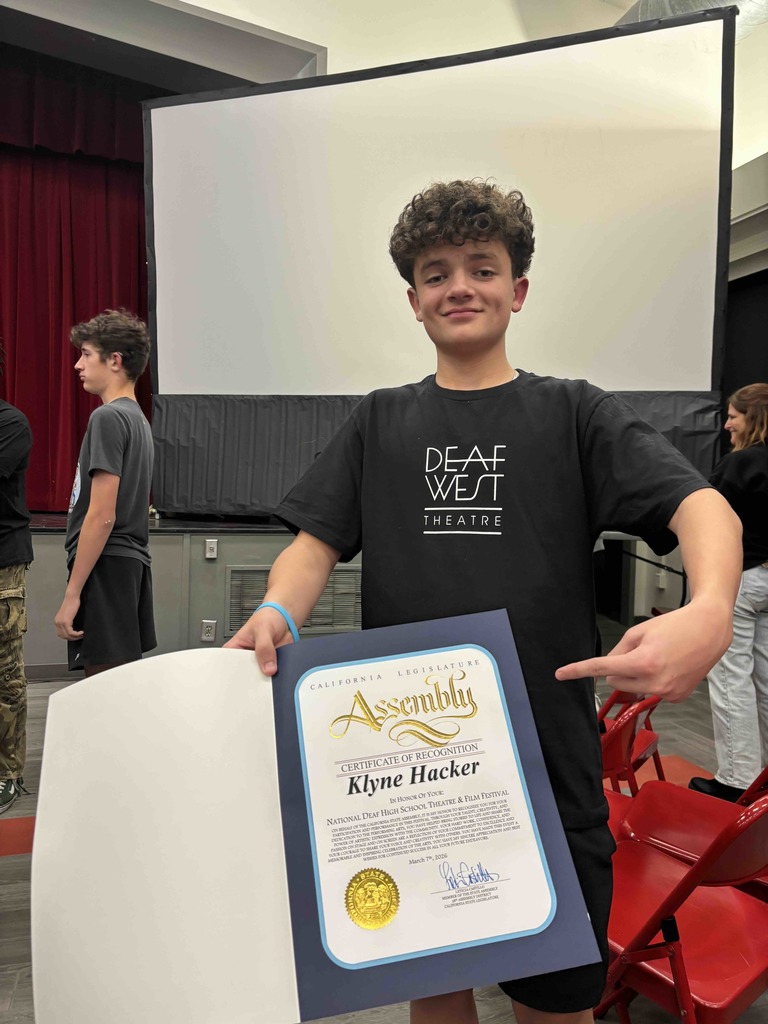 A student smile and hold his certification of recognization for the photo. 