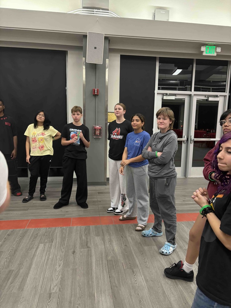 Group of students stand together watching, learning and getting ready to do an theatre exercise. 