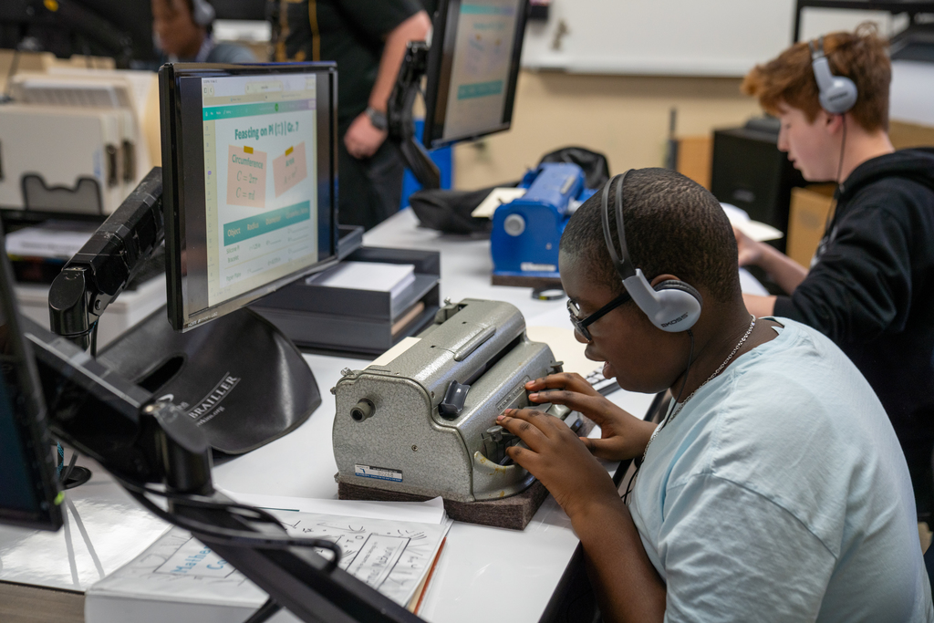 A student works on a math problem sitting down inside the classroom. 