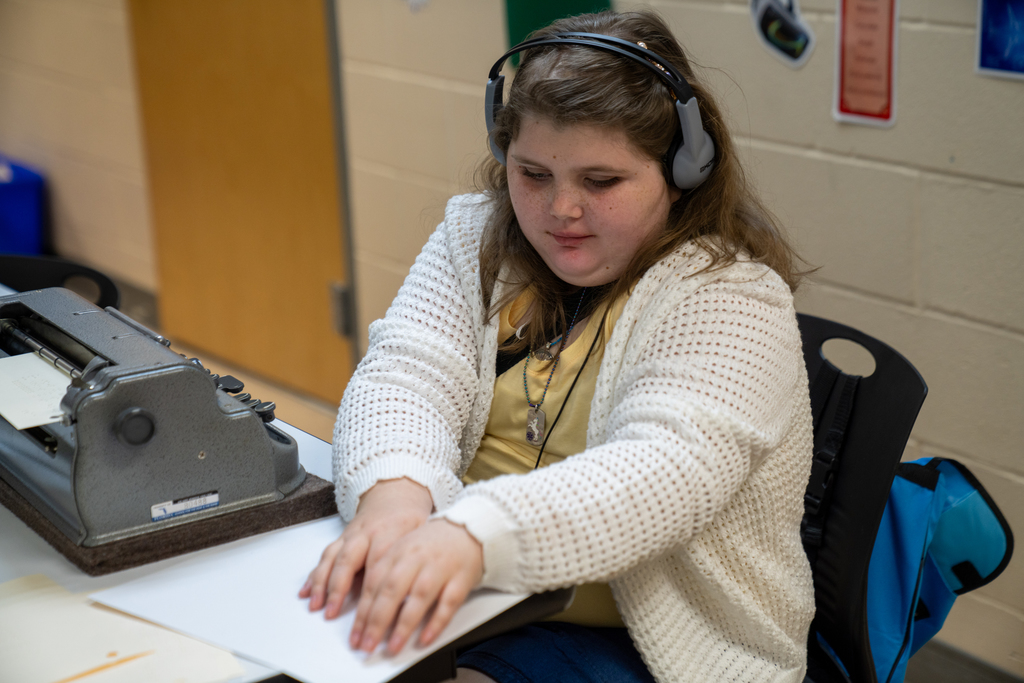 A student works on a math problem sitting down inside the classroom. 