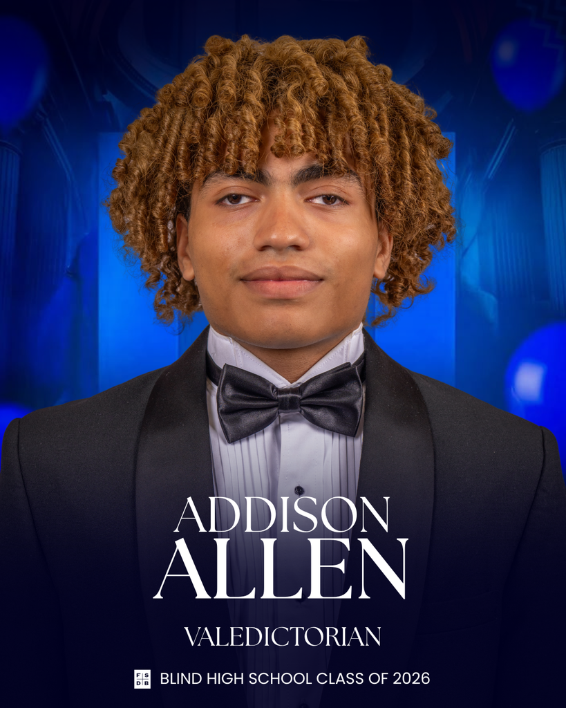 Senior portrait of Addison, wearing a tuxedo in front of a blue background.