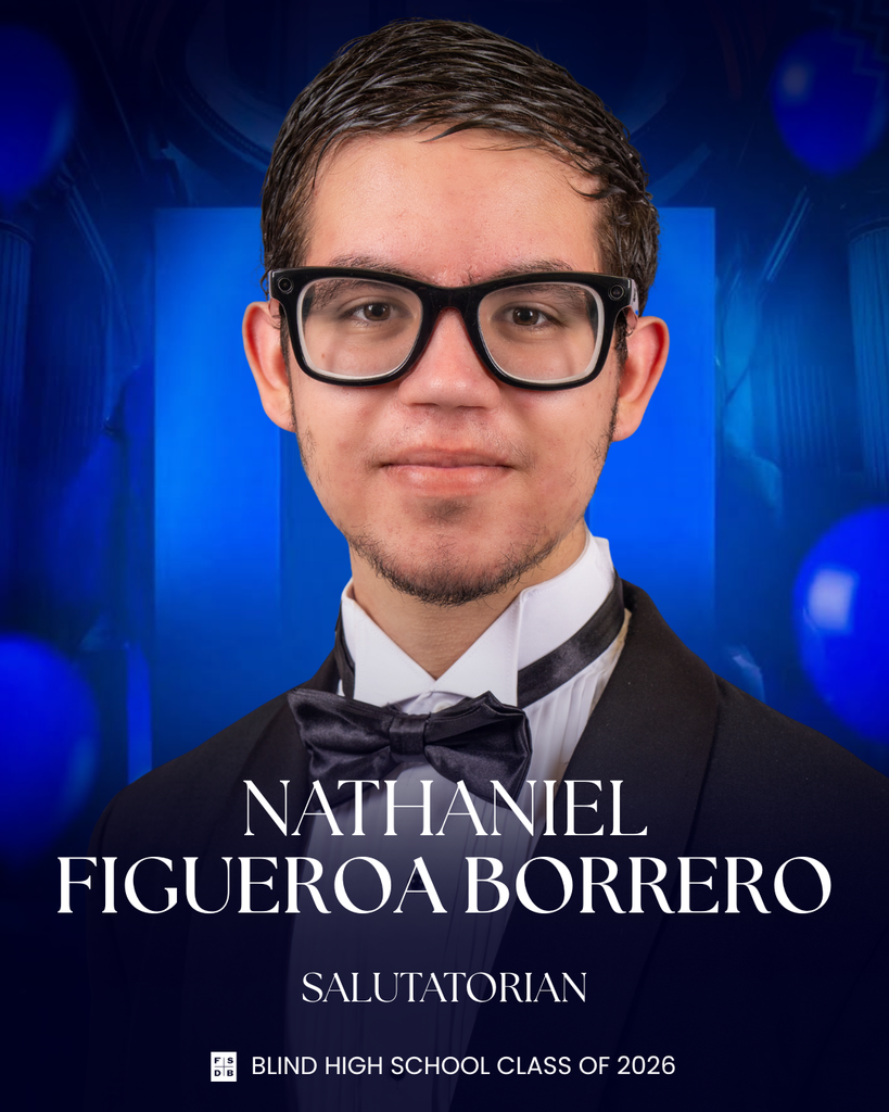 Senior portrait of Nathaniel, wearing a tuxedo in front of a blue background.
