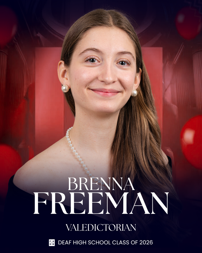 Senior portrait of Brenna, wearing a black drape, a pearl necklace and pearl earrings, in front of a red background.