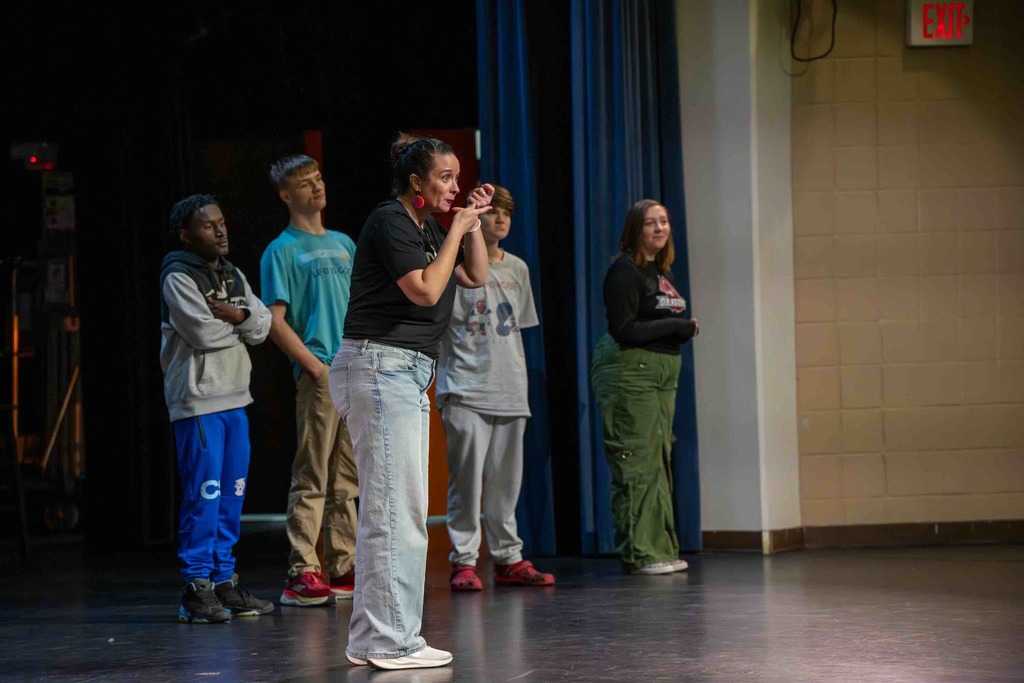 Dr. Renca sign on stage with a few deaf high school students on stage with her inside Kirk.