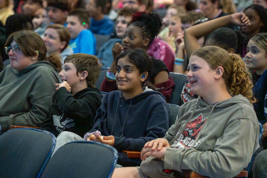Group of middle school deaf students sit and listen to Dr. Renca performance inside Kirk.