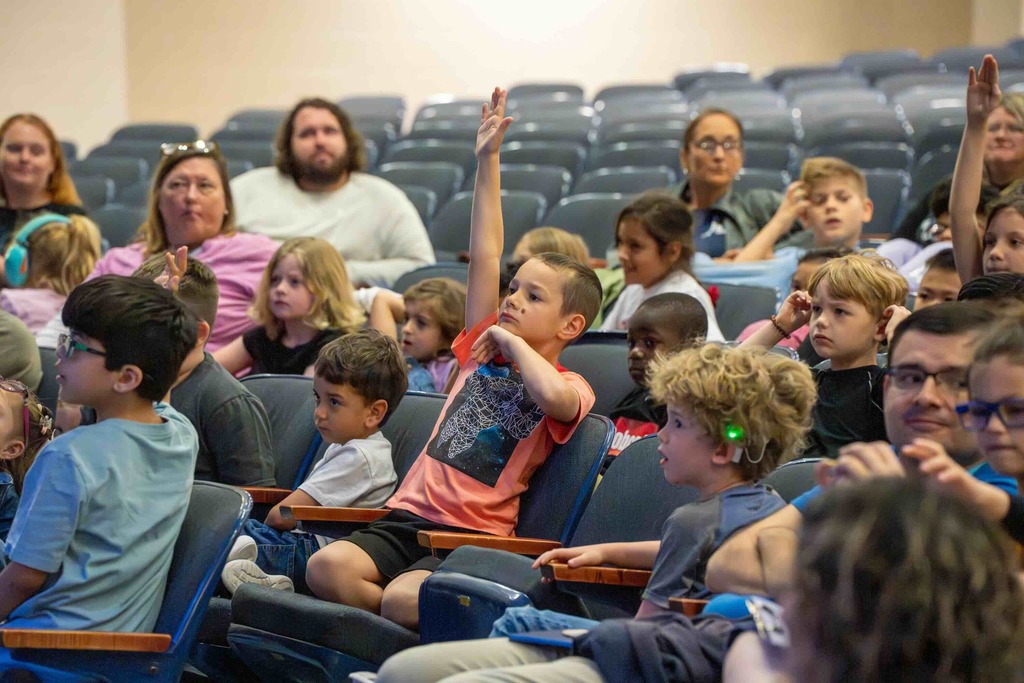 Group of students hold their hands up to volunteer when Dr. Renca asked for volunteers.
