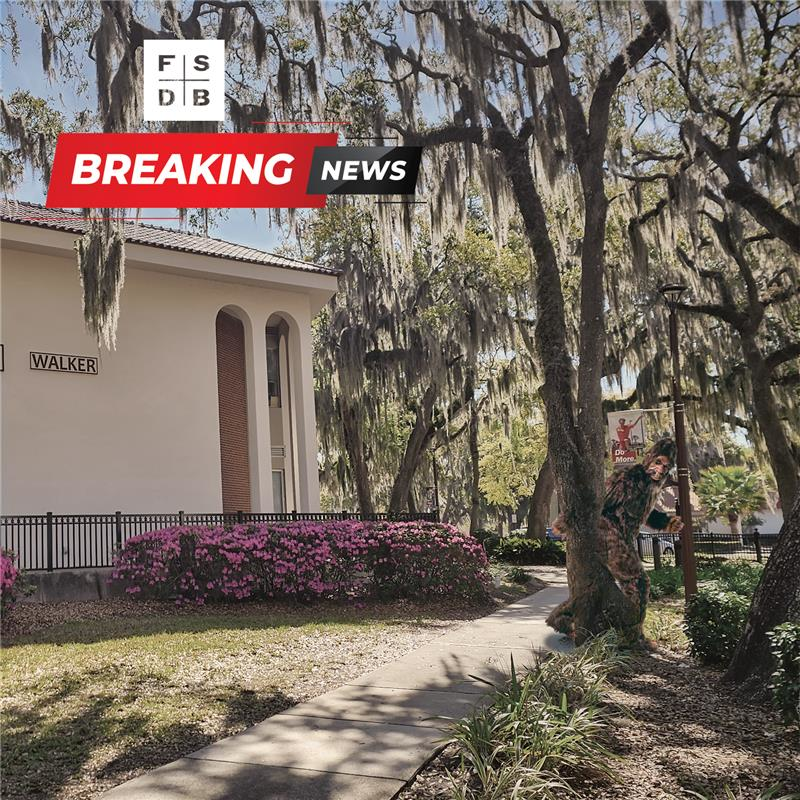 Outdoor photo outside of FSDB Walker building with trees and Big Foot hiding behind the tree.