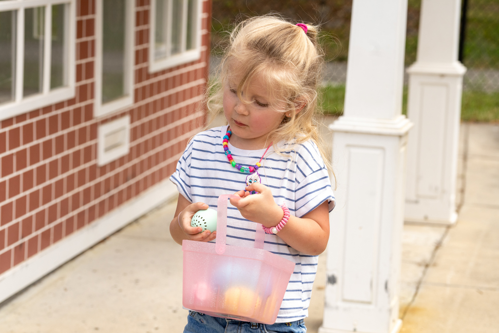 A student holds her pink Easter basket and puts an egg she found inside.