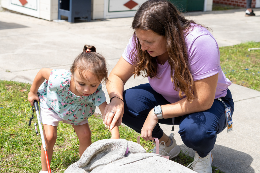 A staff helps a student pick up the easter egg she found outside of Kids Town.