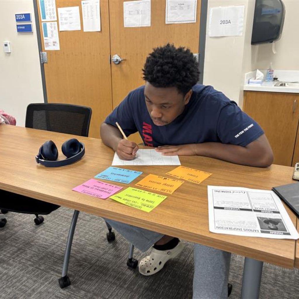 A student writing down his college schedule after choosing the classes with the colorful cards.