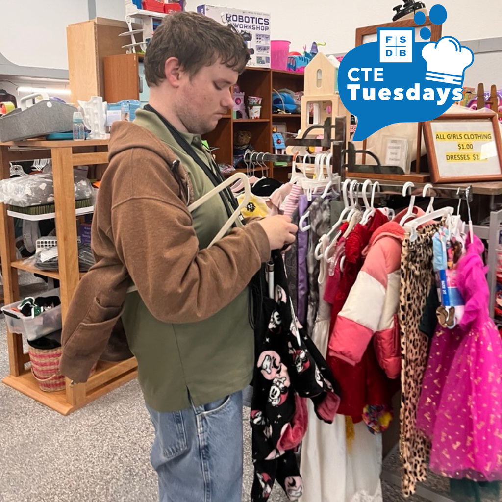 Allan is putting clothes on hangers and rackets inside a store.