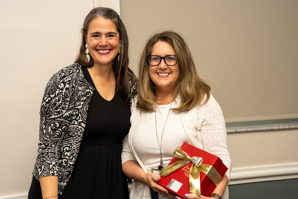 President Tracie Snow is smiling with DMS Teacher of the Year who holds a red gift box inside CLD.