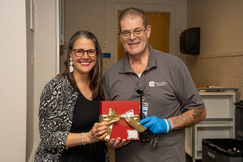 President Snow is smiling with the Student- Related Employee of the Year who is holding the red gift box inside CLD.