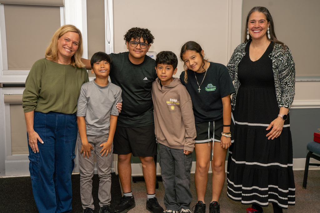 Group of DES students smile with President Snow and their teacher inside CLD.