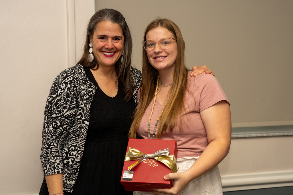 President Tracie Snow is smiling with DHS Teacher of the Year who is holding a red gift box inside CLD.