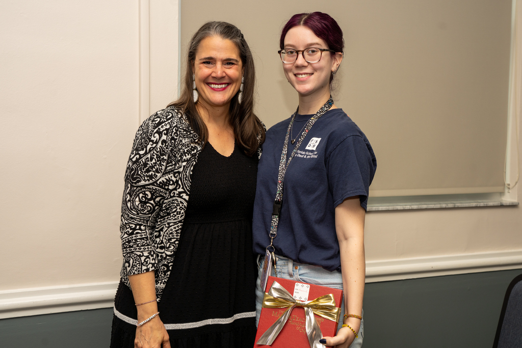 President Snow is smiling with BHS Teacher of the Year who is holding a red gift box inside CLD.