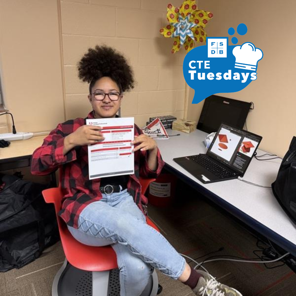 Kyra holds her adobe certification professional inside the classroom.