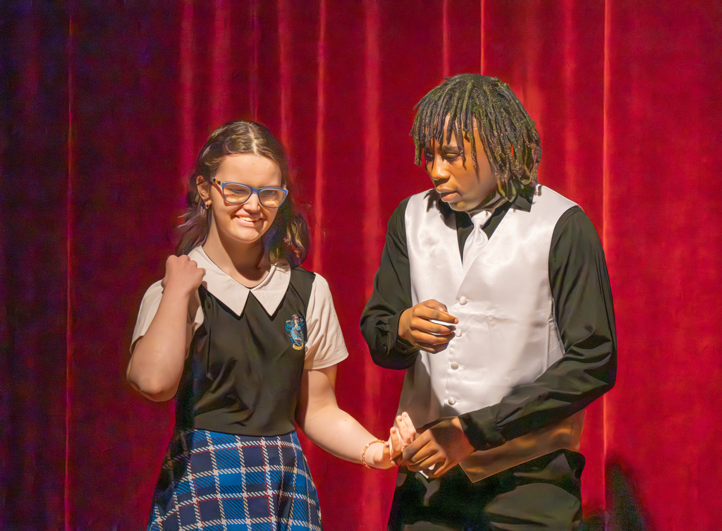 Two students are acting on stage in the Music Building.
