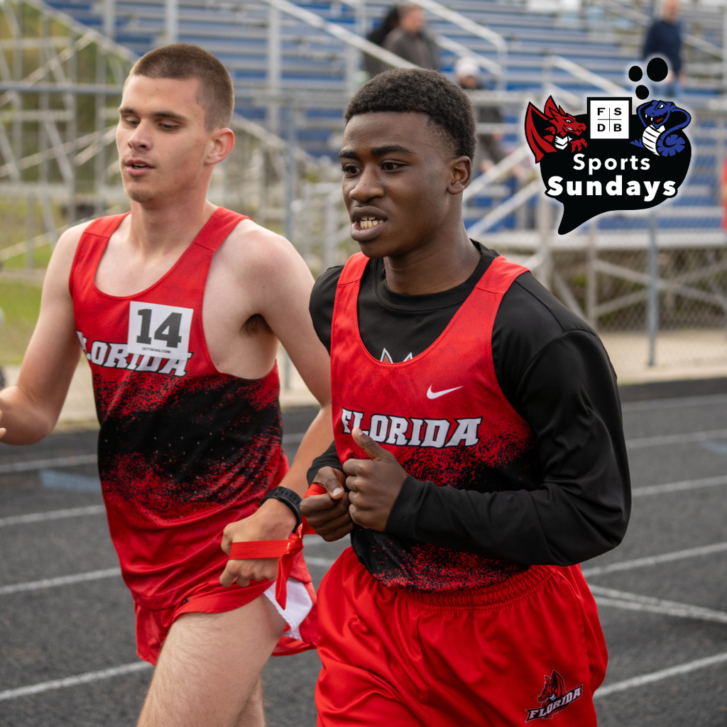 Two track runners side by side running to the finish line. 