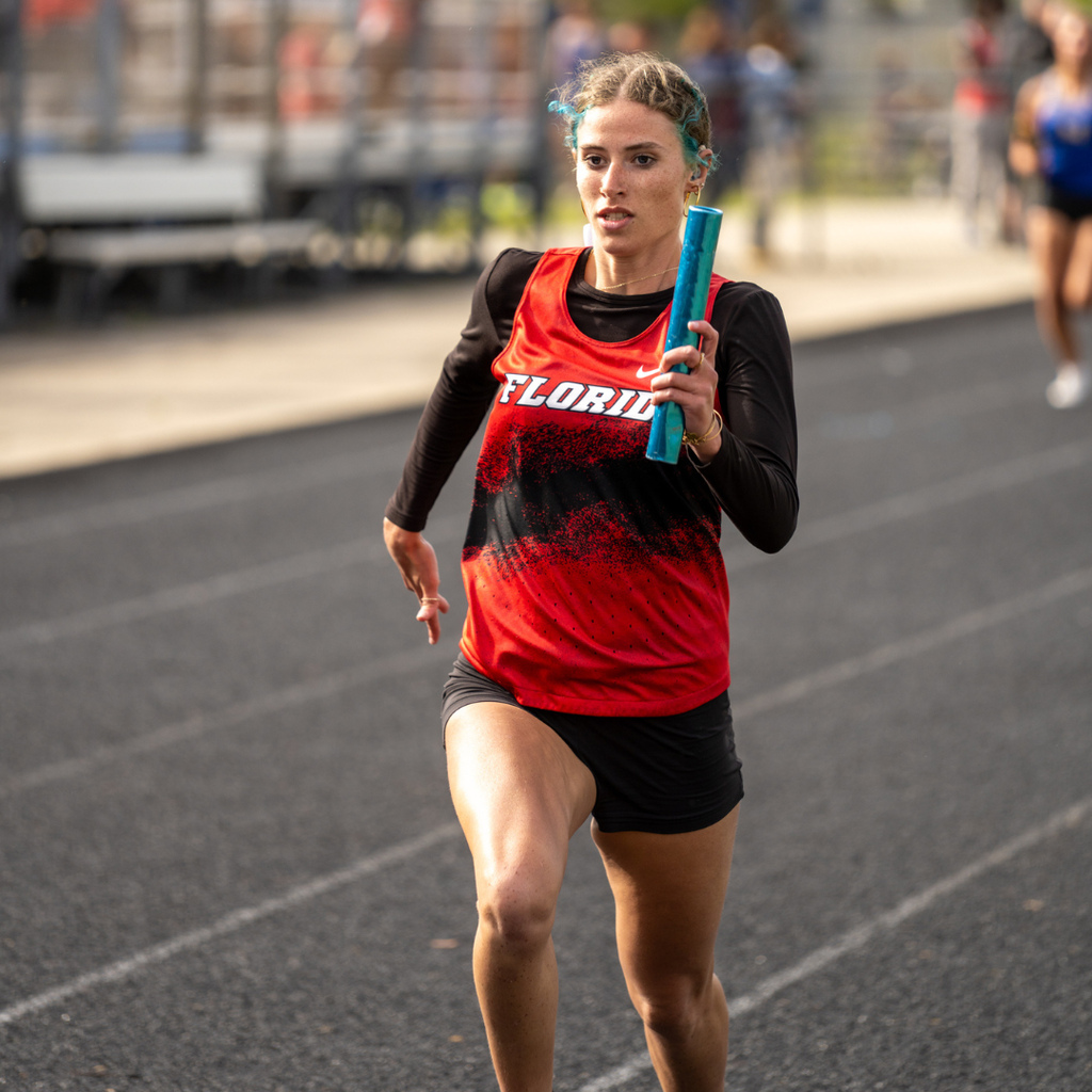 FSDB girl runner runs with a baton in her hands running on the track field. 