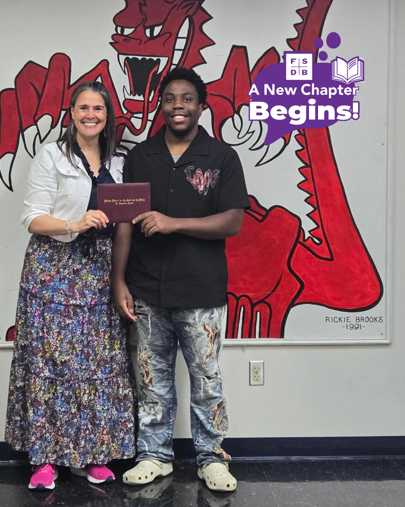 Tyler smiles with President Snow holding his diploma inside the Dragon's Lair. 