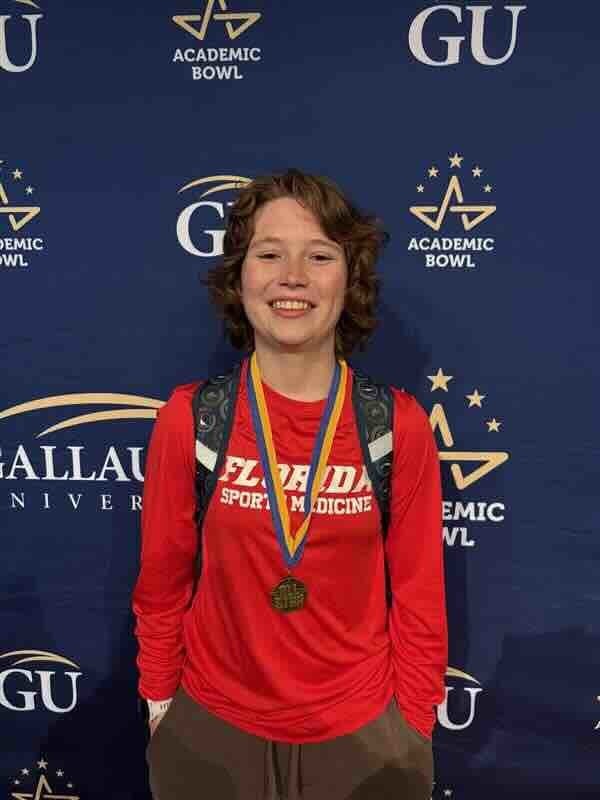 A photo of Joss wearing a medal and smiles for her photo with an Gallaudet University background. 