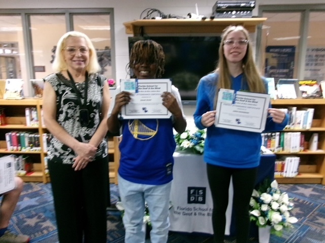 Students smile with their certification with the principal inside the library.