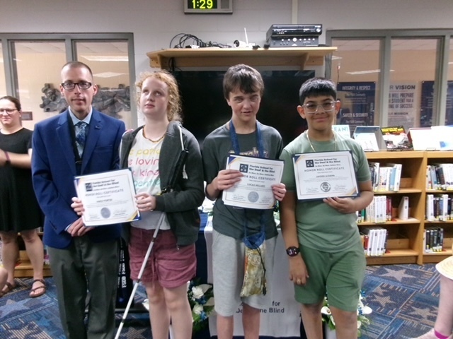 Students smile with Mr. Ferguson holding their certification inside the library.