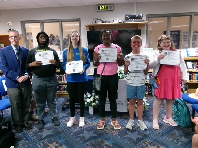Students hold their certification smiles with Mr. Ferguson inside the library. 