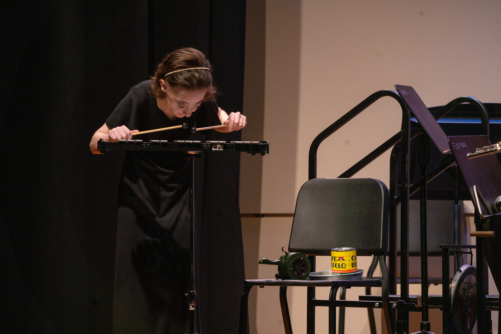 An FSDB student wearing a black concert dress is standing and playing xylophone on stage in the Music Building. 