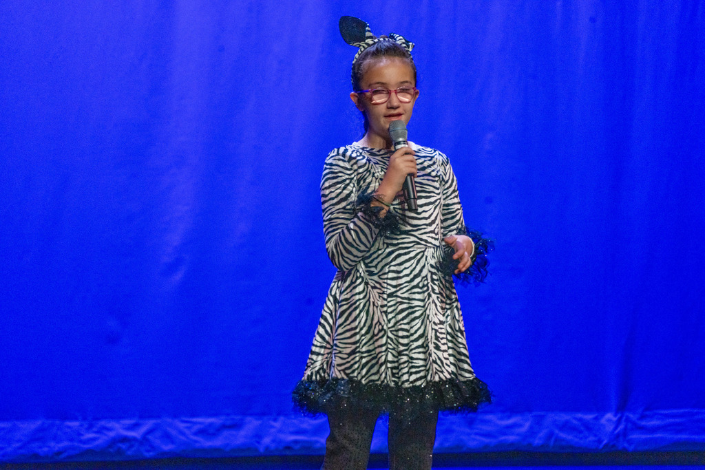 Blind Elementary student dressed like a zebra singing on stage in Kirk. 