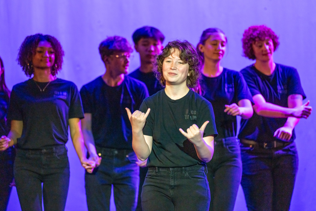 FSDB Dance troupe student signs "Now" on stage surrendering by her peers in Kirk.