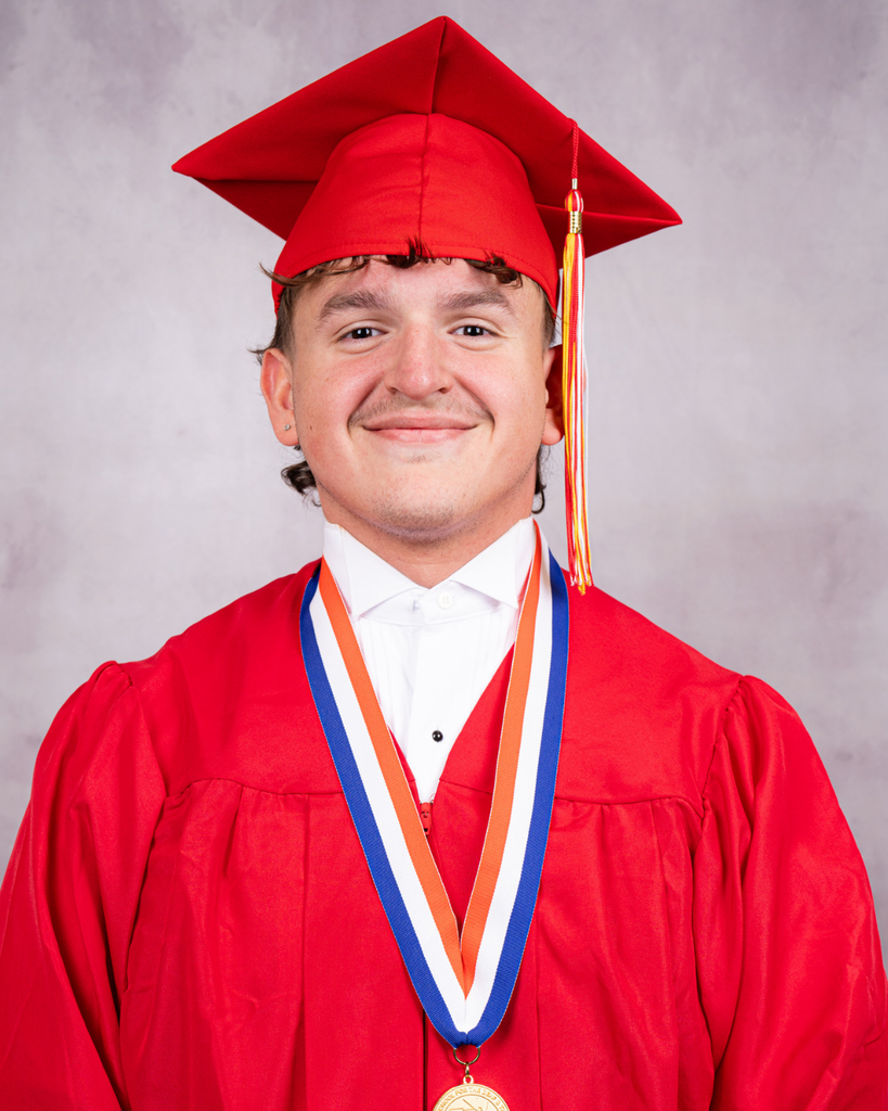 Eduardo is wearing a red cap and gown smiles for his photo. 