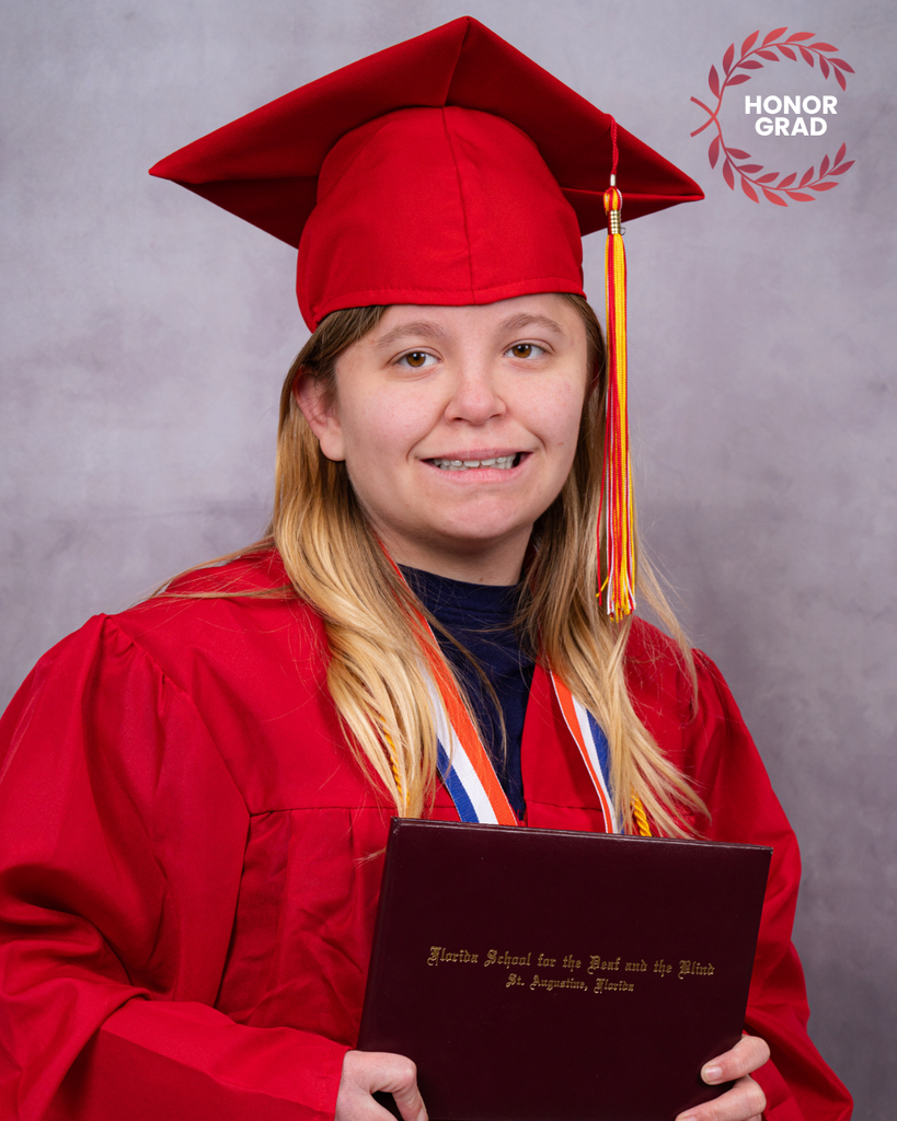 Lauren is holding her diploma smiles in her red cap and gown. 