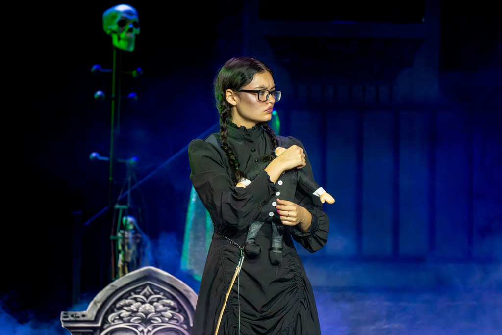 A dance troupe performer dressed in a black dress holding a black doll perform on stage in Kirk.
