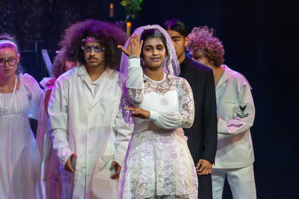 A girl dressed in a white wedding dress sign and perform on stage in Kirk. 