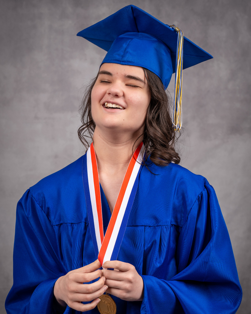 Caitlin smiles for her photo in her blue cap and gown.