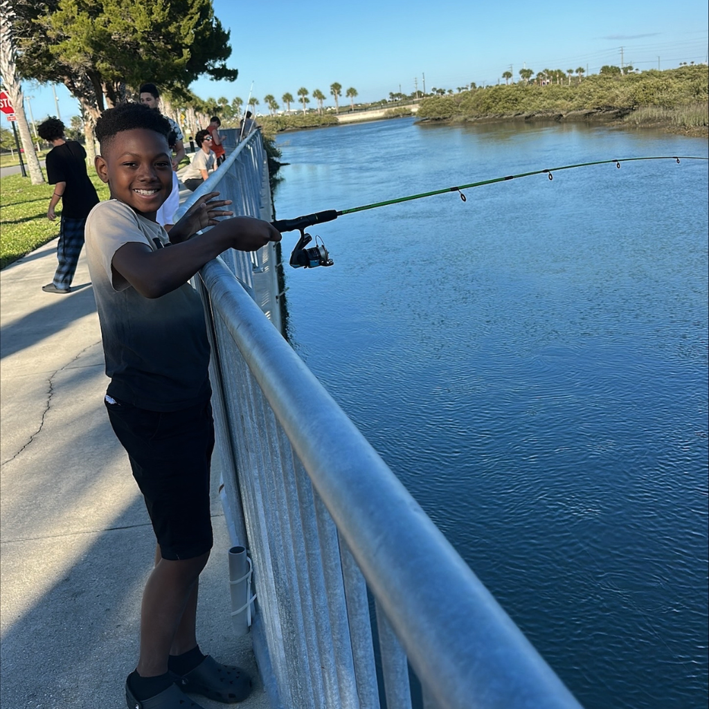 A boy smile got his photo as he holds his fishing rod waiting for a fish outside by the water at FSDB.