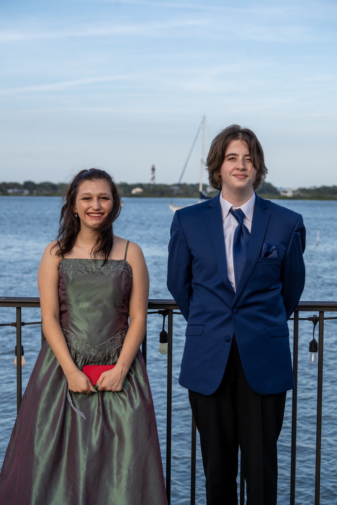 A prom date couple smile for their photo outside of River House by the water. 