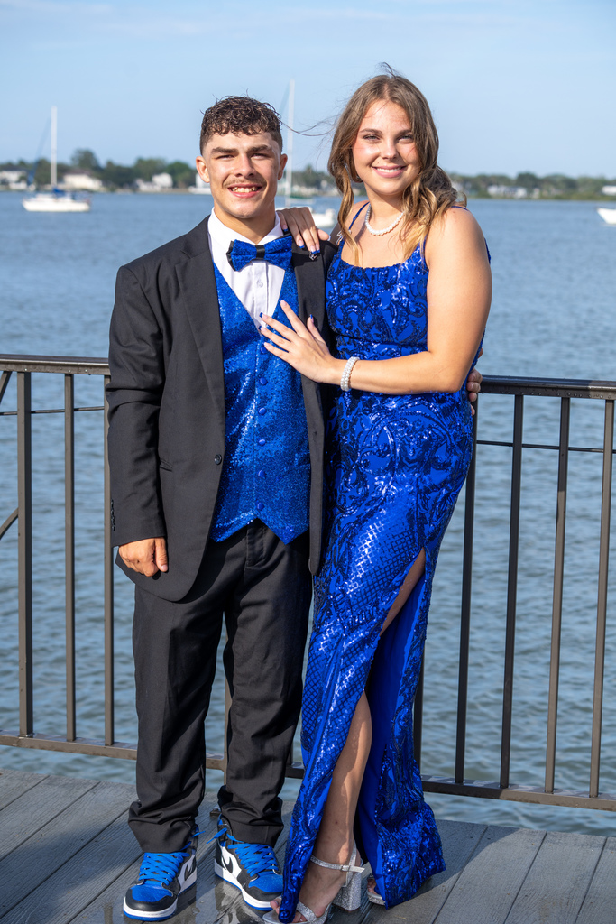 Prom date couple dressed in blue smile for a picture outside of River House by the water. 