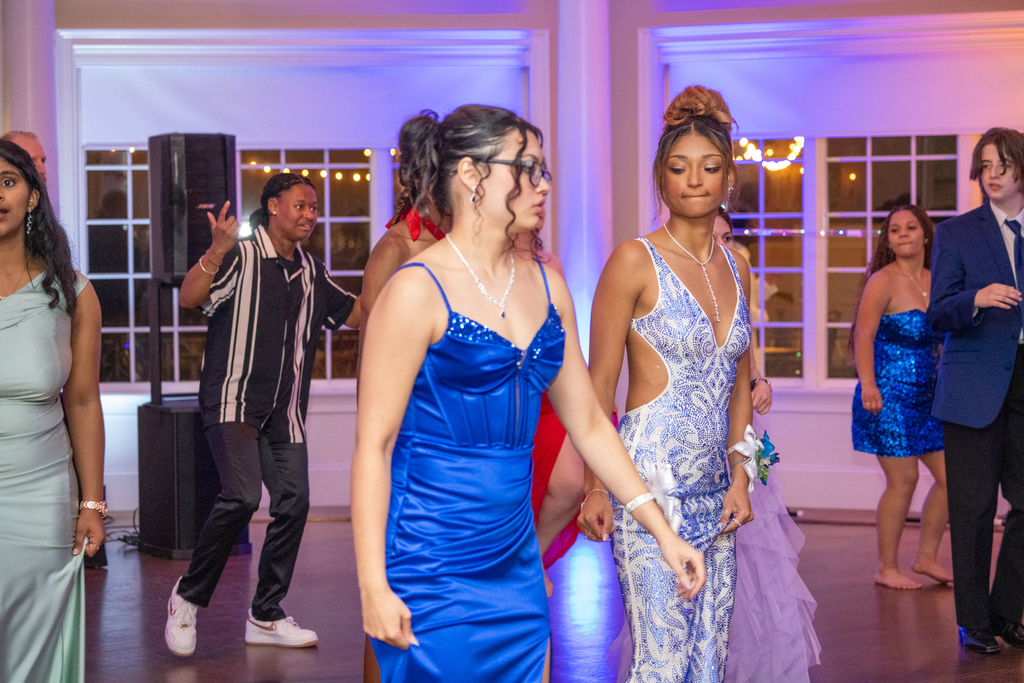 Two students dressed in prom dresses dance on the dance floor inside River House. 