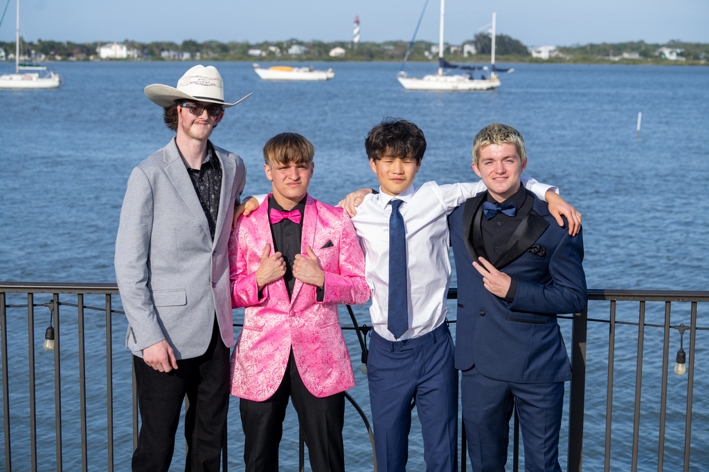 Group of friends smile for a photo outside of River House by the water. 