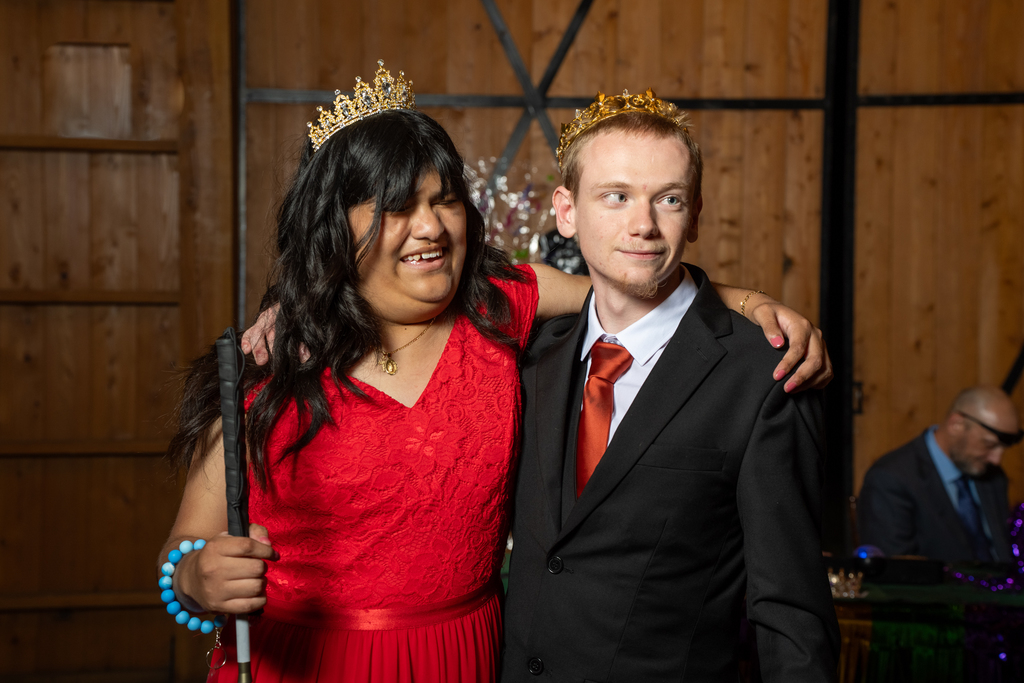 Prom Princess and Prince smile together for a photo inside the barn. 