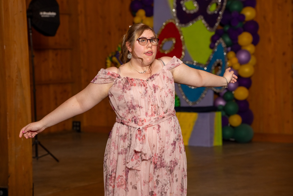 A student dressed in pink floral dances on the dance floor inside the barn. 